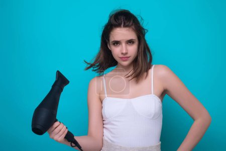 Téléchargez les photos : Woman with hair dryer on studio background. Girl hold hairdryer. Young woman drying hairs with hair dry machine. Beauty girl using dries hairs with hair dryer. Beauti model with holding blow dryer - en image libre de droit