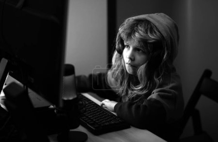 Photo for Kid boy hacker, young programmer. Child playing computer games or studying on pc computer. Kid gamer on night neon lighting - Royalty Free Image