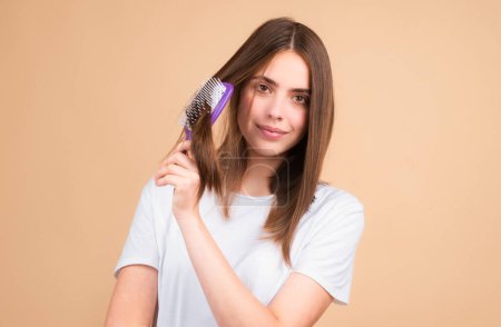 Photo for Young woman combing healthy and shiny hair, isolated on studio - Royalty Free Image