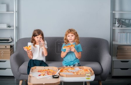 Photo for Funny kids eating pizza. Two young children bite pizza indoors - Royalty Free Image