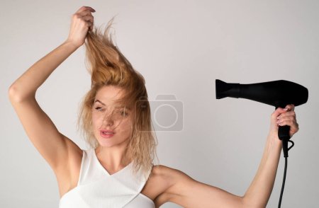 Téléchargez les photos : Femme utilisant un sèche-cheveux, sèche-cheveux. Jeune femme avec sèche-cheveux avec machine sèche-cheveux - en image libre de droit
