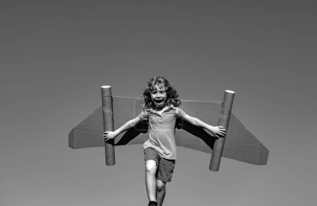 Photo for Happy child playing in park. Kid having fun with toy paper wings. Little boy in dreaming of becoming a pilot. Funny kid on a sky blue background with copy space - Royalty Free Image