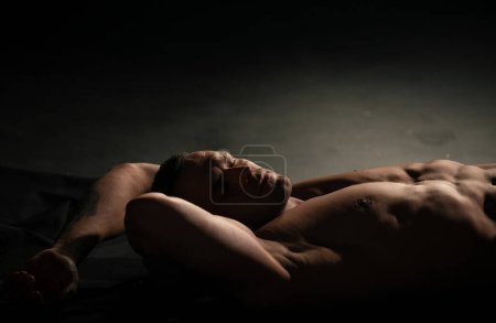 Téléchargez les photos : Sexy homme musclé nu avec six abdos pack couché dans le lit. Attrayant jeune gay. Concept bien-être, bien-être - en image libre de droit