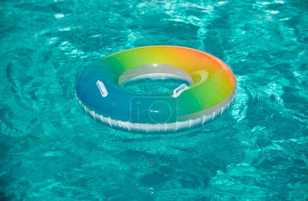 Photo for Pool float, rainbow ring floating in a refreshing blue swimming pool. Inflatable ring floating in pool on summer background - Royalty Free Image