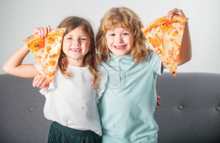 Photo for Hungry children eating pizza. Happy excited children eating pizza and having fun together. Happy kids holding pizza slice near face - Royalty Free Image