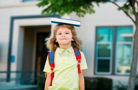 Photo for Back to school. Funny little boy in glasses near school. Child from elementary school with book and bag. Education. Kid with a book - Royalty Free Image