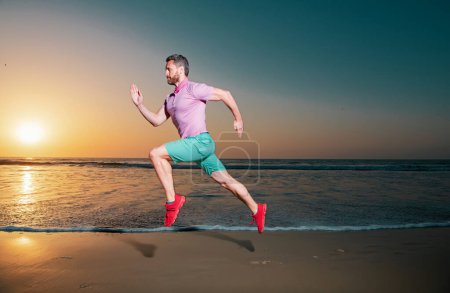 Photo for Man running on the beach at sunset. Sport and healthy lifestyle. Athlete running around the beach line near the sea. Fit runner on the beach with sea background. Beach activities concept - Royalty Free Image
