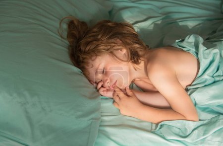 Téléchargez les photos : Enfants mignons dormant au lit et couchés sur des oreillers doux - en image libre de droit