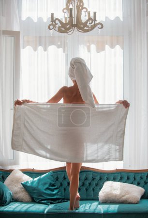 Photo for Perfect young woman body with towel after shower. Back view of sexy girl resting in the luxury bedroom an easy morning. Attractive sensual woman relaxing wearing bathrobes and towels in luxury room - Royalty Free Image