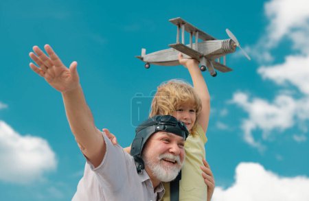 Foto de Viejo abuelo y nieto niño pequeño divertirse con avión de juguete en el cielo. Sueños infantiles de volar, infancia feliz con el abuelo - Imagen libre de derechos