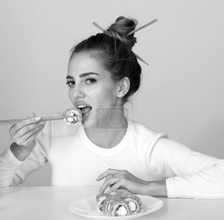 Foto de Sexy woman eat japanese traditional food sushi rolls. Girl is holding japanese sushi piece of roll philadelphia by chopsticks. Advert for sushi delivery of restaurants cafe - Imagen libre de derechos