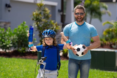 Photo for Sporty family. Little kid learning to ride bicycle with father in park. Father teaching son cycling. Father and son learning to ride a bicycle at Fathers day. Father support helping son. Child care - Royalty Free Image