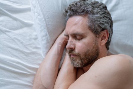 Téléchargez les photos : Un homme dormant dans un lit blanc. Sexy homme torse nu dormant dans le lit dans la chambre. Homme mûr hispanique dormant à la maison le matin. Bon sommeil. Un homme qui dort au lit. Les gens dorment, dorment - en image libre de droit