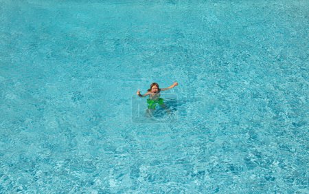 Téléchargez les photos : Éclaboussures d'enfants dans la piscine d'eau d'été. Un petit plongeon dans la piscine. Heureux petit garçon excité sautant dans la piscine, amusant de l'eau. Saut d'enfant dans la piscine et éclaboussures d'eau. éclaboussures d'enfants au bord de la piscine - en image libre de droit