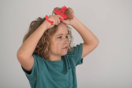 Photo for Funny hairstyle. Kids hair care concept. Portrait of kid brushing her unruly, tangled long hair on isolated studio background - Royalty Free Image