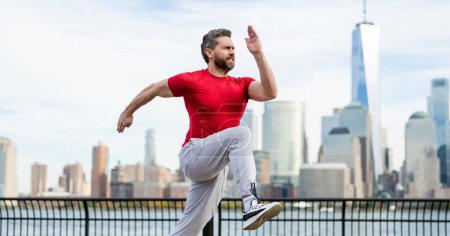 Téléchargez les photos : Homme coureur en tenue de sport courir à New York. Mouvement, course saine. Un joggeur mature court près de Manhattan. Athlète sportif musclé courir en ville. Courir des vêtements de sport. beau gars courir séance d'entraînement extérieur - en image libre de droit