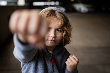 Photo for Kid boy in hoodie fighting. Little kid boy fighting outside. Angry little boy showing fist and fighting outdoor. Portrait of fighting kid. Bad Children fight. Aggression little boy. Bad behavioral - Royalty Free Image