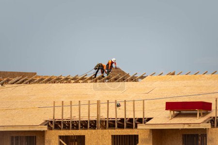 Foto de Viga de techo de madera de marco. Techo de la casa en la construcción. Roofer trabajando en la estructura del techo del edificio en el sitio de construcción. Vigas de madera. Clavos para techos o tornillos para hojas OSB - Imagen libre de derechos