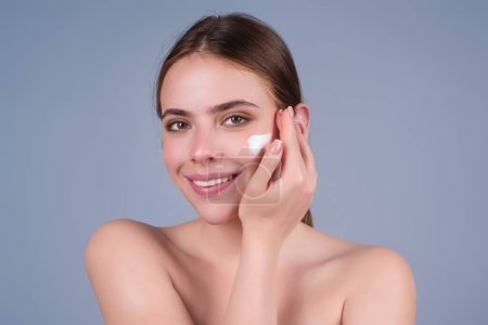 Téléchargez les photos : Woman putting cosmetic cream. Spa model applying skincare product on her face. Morning make-up. Moisturizing skincare cream, lotion or mask for skin lifting and anti-aging effect - en image libre de droit