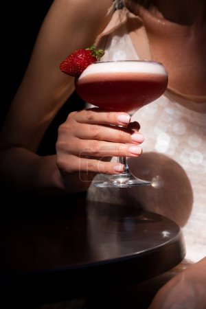 Foto de Cóctel de verano. Copa de cóctel de margarita alcohólica con fresa cerca del modelo femenino borroso, de cerca - Imagen libre de derechos