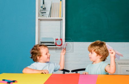 Photo for Funny toddlers from elementary school hold paper plane laughing and smiling. Kids funny education. Preschool childrenhaving fun in classroom. First time to school. Kid gets ready for school - Royalty Free Image
