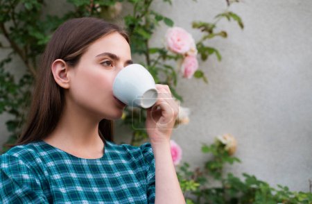 Téléchargez les photos : A young girl drinks coffee. Young stylish woman drinking cappuccino, enjoying spring, romantic girl - en image libre de droit