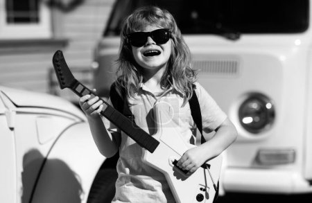 Foto de Muchacho emocionado con instrumentos musicales. El niño caucásico toca la guitarra. Niños misic - Imagen libre de derechos