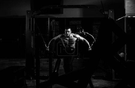 Photo for Strong muscular man works out pushing up excercise in gym, exercises at triceps. Crossfit, sport and healthy lifestyle concept - Royalty Free Image