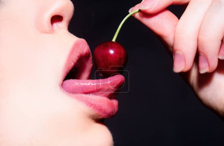 Cherry in woman mouth. Summer sexy fruits. Cherries on woman lips. Tongue lick cherry, macro, close up