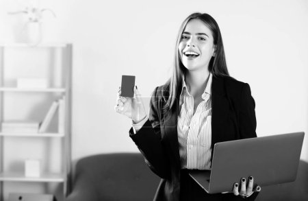 Téléchargez les photos : Heureuse femme d'affaires avec carte de crédit portable au bureau. Services financiers, concept bancaire par carte de crédit - en image libre de droit