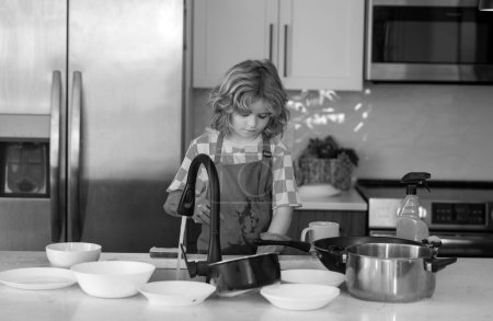 Photo for Clean dishes. Little housekeeper. Child washing and wiping dishes in kitchen. American kid learning domestic chores at home. Kid cleaning to help parents with housework routine. Boy housekeeping - Royalty Free Image