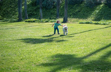 Téléchargez les photos : Child running with a dog. Kid with a puppy dog outdoor playing at backyard lawn. Carefree childhood - en image libre de droit