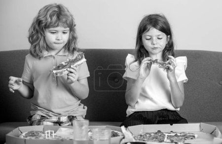 Téléchargez les photos : Des gamins drôles mangeant de la pizza. Petite fille et garçon manger de la pizza - en image libre de droit