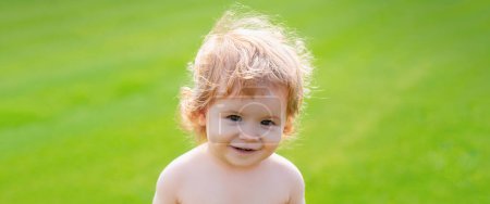 Téléchargez les photos : Bannière avec le visage d'enfant de ressort. Petit bébé en couches jouant dans la nature sur l'herbe verte. Bébé et été temps ensoleillé. Enfant blond, émotion riante, visage souriant heureux - en image libre de droit