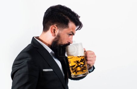 Téléchargez les photos : Un homme en costume classique buvant de la bière. Barbu gars en tenue de travail semble heureux et satisfait. Portrait d'homme avec haut verre de bière levé isoalté sur blanc - en image libre de droit