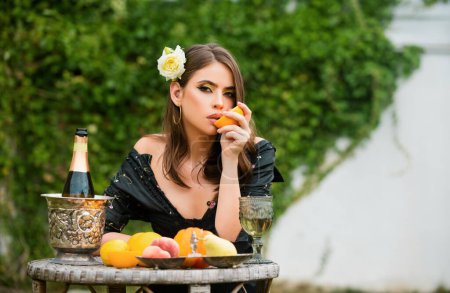Photo for Summer portrait of beautiful fashion woman eating orange, summer fruits, outdoor. Beautiful woman enjoying spring, pretty girl relaxing in garden. Sexy woman squeezing juice from fresh orange - Royalty Free Image