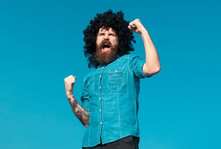 Photo for Funny nerdy guy. Crazy funny bearded man with wig on sky background. Expression and success - Royalty Free Image