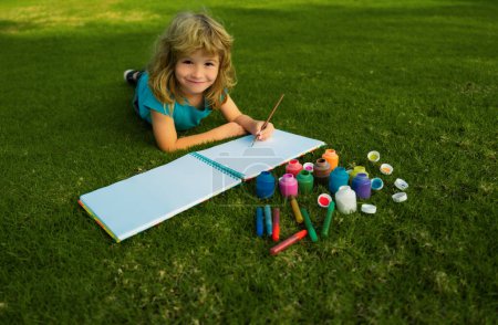 Téléchargez les photos : Peinture pour enfants avec peinture couleur et pinceau dans le parc en plein air. Joyeux enfant jouant dehors. Dessin thème d'été. Imagination concept enfants - en image libre de droit
