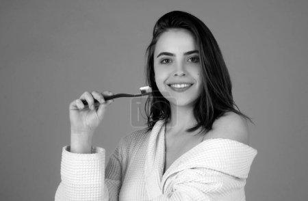 Photo for Beautiful young smiling woman with healthy teeth, beautiful female smile. Dental concept. Smiling young woman brushing teeth using toothbrush with whitening toothpaste, cleaning teeth in the morning - Royalty Free Image