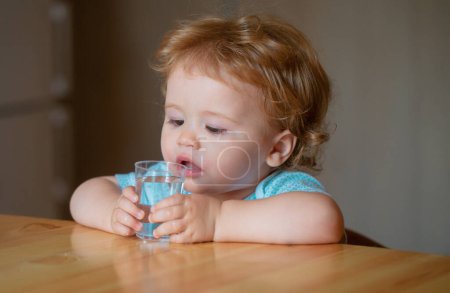 Photo for Healthy nutrition for kids. Baby drink water. Portrait of a sweet Beautiful child drinking a glass of water - Royalty Free Image