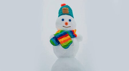 Foto de Feliz muñeco de nieve sonriente en el soleado día de invierno. Ropa de invierno, sombrero de punto y bufanda - Imagen libre de derechos