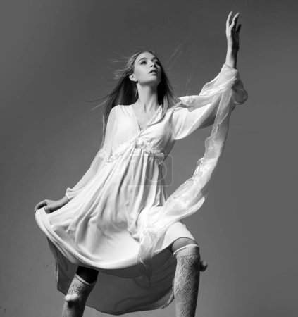 Téléchargez les photos : Movement model in white dress. Fashion shot. Vogue model posing at studio. Collection of fashion clothes - en image libre de droit