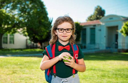 Foto de Concepto de niño escolar. Alumno lindo, niño en uniforme escolar con mochila al aire libre. Retrato de colegial nerd - Imagen libre de derechos