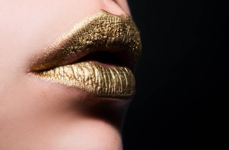 Foto de Labios sexy. Primer plano sexy hermosa hembra labios dorados aislados. Lápiz labial dorado - Imagen libre de derechos
