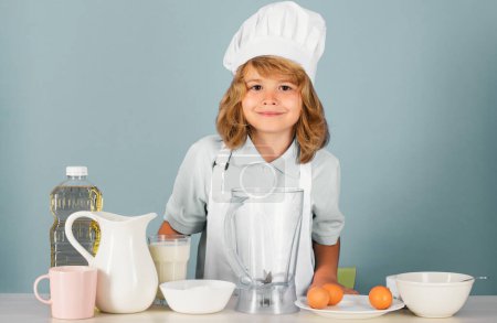 Foto de Cocinar niños. Chef niño haciendo verduras frescas para comer sano. Retrato de niño pequeño en forma de cocinero aislado sobre fondo gris. Chef de niños. Proceso de cocción - Imagen libre de derechos