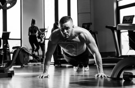Photo for Sport man doing push ups exercise, pushup crunch. Portrait of young athlete doing exercise with dumbbell at the gym. Crossfit, sport and healthy lifestyle concept - Royalty Free Image