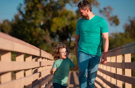 Téléchargez les photos : Père avec fils marchant sur un pont boisé en plein air - en image libre de droit