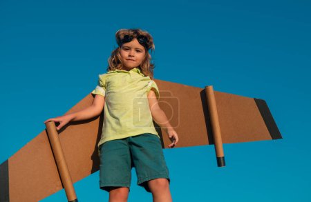 Photo for Child playing with toy jetpack on sky. Child pilot astronaut or spaceman dreams of flight. Aviator boy flying with a cardboard wings - Royalty Free Image