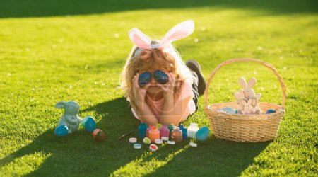 Téléchargez les photos : Joyeux lapin de Pâques enfant garçon couvrir les yeux avec des œufs. Concept vacances printemps enfants - en image libre de droit