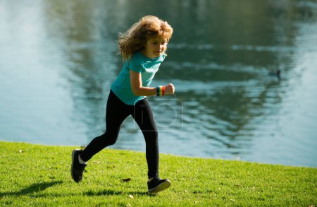 Téléchargez les photos : Enfant garçon courant dehors. Enfant coureur joggeur courir dans la nature. Bonjour, jogging. Mode de vie sain et actif des enfants. Course matinale avec enfants - en image libre de droit